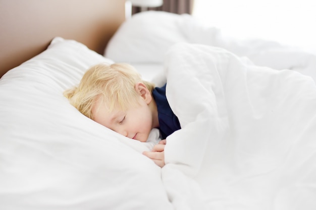 Mignon petit garçon endormi Enfant fatigué, faire la sieste dans le lit des parents.