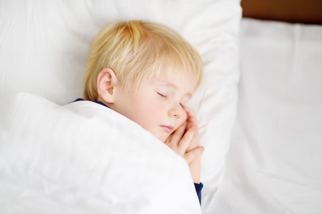 Mignon petit garçon endormi Enfant fatigué, faire la sieste dans le lit des parents.