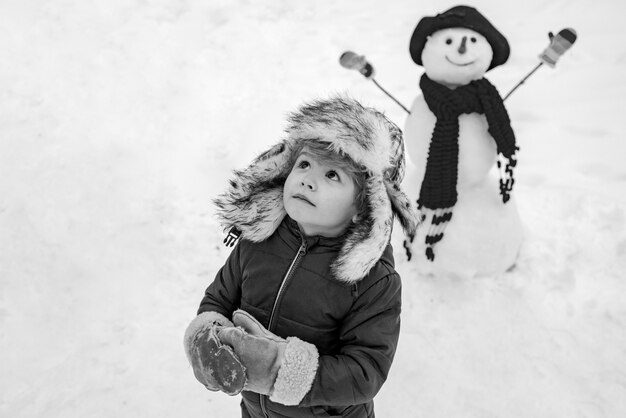 Mignon petit garçon enfant sur champ enneigé en plein air