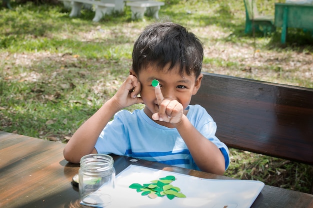 Mignon petit garçon fait des devoirs dans un parc verdoyant