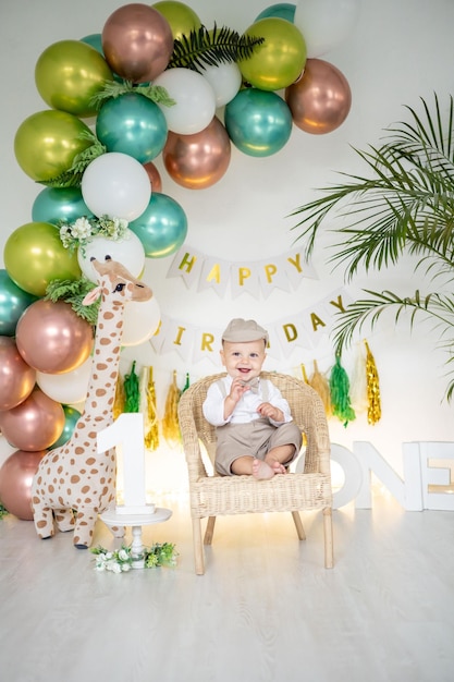 Un mignon petit garçon fête son premier anniversaire sur fond de ballons aux couleurs vives et d'accessoires festifs pour les premières vacances des enfants