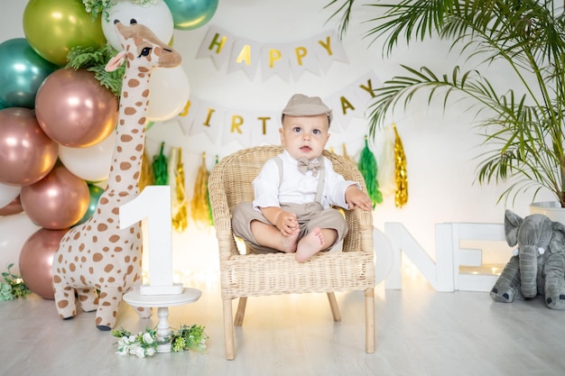 Un mignon petit garçon fête son premier anniversaire sur fond de ballons aux couleurs vives et d'accessoires festifs pour les premières vacances des enfants