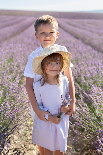 Mignon petit garçon et fille dans un champ de lavande au coucher du soleil