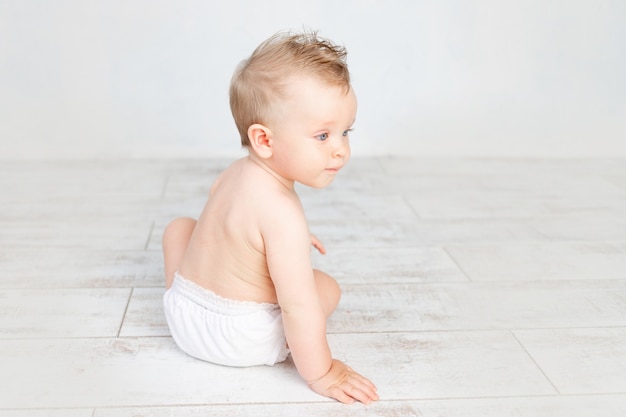 Mignon petit garçon sur fond blanc avec une coiffure et de grands yeux bleus en couches sur fond blanc avec une coiffure, vue arrière