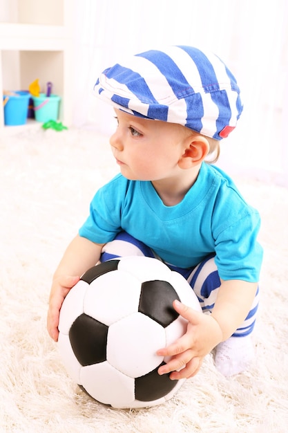 Mignon petit garçon avec football dans la chambre