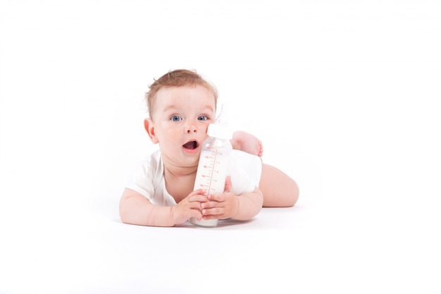 mignon petit garçon heureux en chemise blanche tenir une bouteille de lait