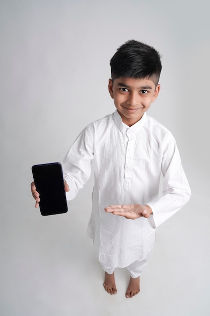 Mignon petit garçon indien montrant l'écran du téléphone intelligent avec copie espace sur fond blanc