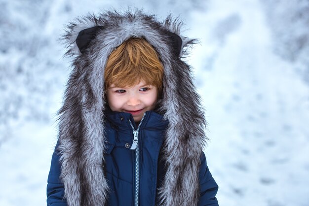 Mignon petit garçon jouant dans un parc d'hiver dans la neige à l'extérieur garçon rêve de l'heure d'hiver bien habillé enjo...