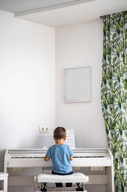 Mignon petit garçon jouant du piano électrique blanc forte appuyant sur les touches kid étudiant à l'école de musique