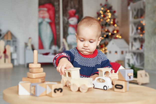 Mignon petit garçon joue avec train en bois jouet, voiture jouet, pyramide et cubes, concept de développement d'apprentissage. Développement de la motricité fine des enfants, de l'imagination et de la pensée logique