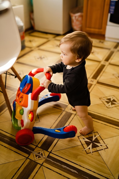 Mignon petit garçon avec marcheur de jouets à l'intérieur de la maison