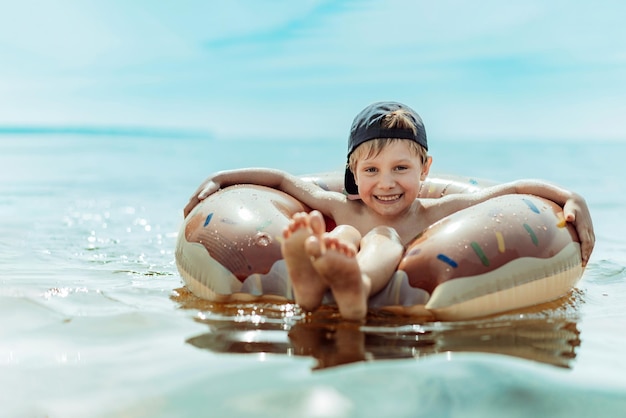 Mignon petit garçon nageant en mer sur un anneau en caoutchouc