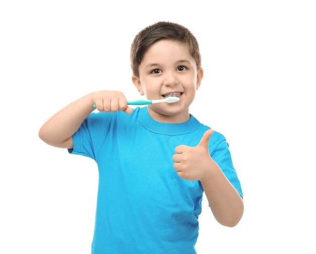 Mignon petit garçon nettoyant les dents sur fond blanc