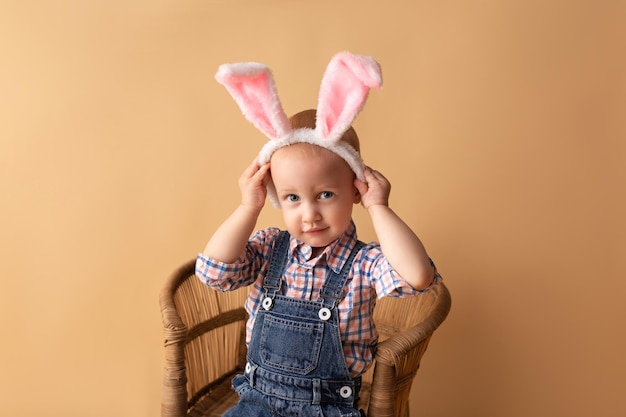 Mignon petit garçon avec des oreilles de lapin sur fond beige Joyeuses Pâques