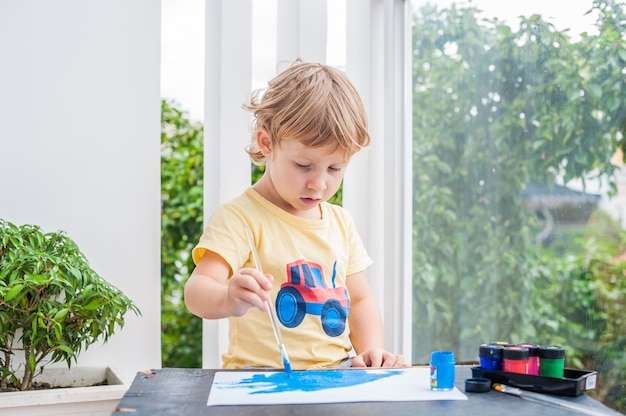 Mignon petit garçon peinture avec des peintures colorées