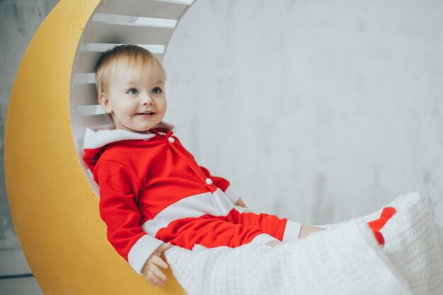 Mignon petit garçon portant le costume de Santa sur un croissant de lune