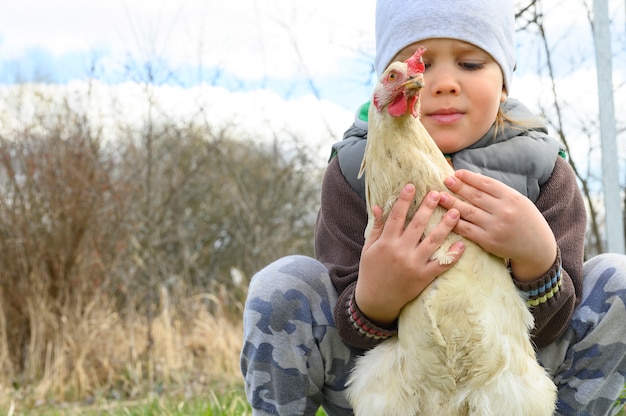 Mignon petit garçon de quatre ans kid tenant dans les mains un poulet blanc dans la nature en plein air