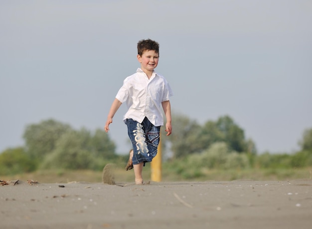 mignon petit garçon qui court sur la plage et s'amuse