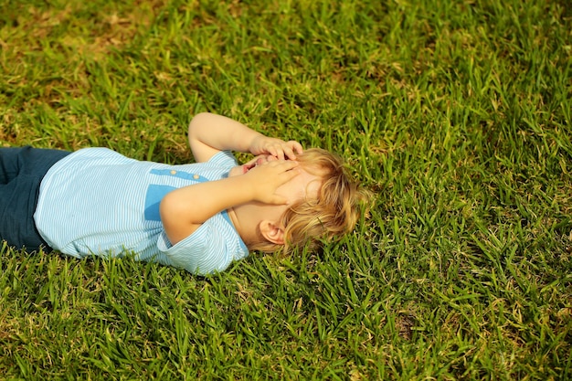 Un mignon petit garçon qui pleure cache le visage avec les mains