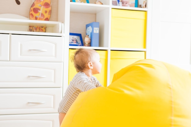 Mignon petit garçon riant heureux jouant sur une chambre blanche.