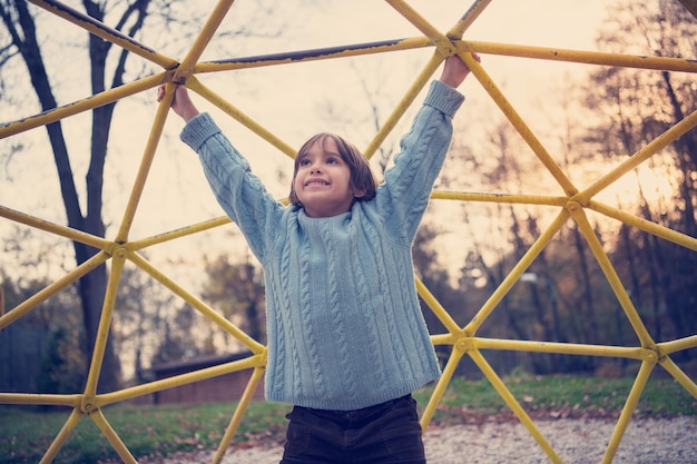 mignon petit garçon s'amusant dans le parc de jeux le jour de l'automne cludy