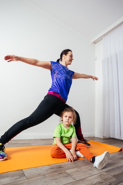 Mignon petit garçon s'ennuie pendant que sa mère fait du yoga le matin