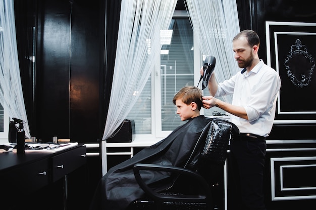 Un mignon petit garçon se coupe les cheveux chez le coiffeur