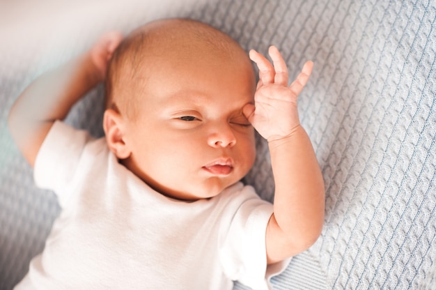 Mignon petit garçon se réveiller dans son lit en gros plan