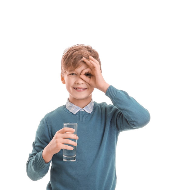 Mignon petit garçon avec un verre d'eau sur blanc