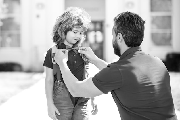 Mignon petit nerd américain père et fils marchant dans le parc de l'école