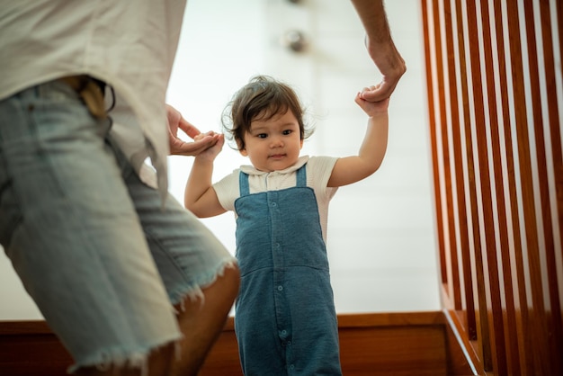 Mignon tout-petit petit enfant concept de famille bébé apprenant à marcher avec le père et la mère pour aider à prendre soin et à tenir la main première étape avec le soutien des parents d'enfance petit amour portrait petit garçon à la maison