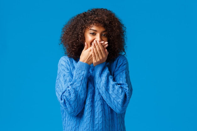 Photo mignonne et idiote, belle femme afro-américaine avec coupe de cheveux afro, riant en souriant et couvrant la bouche en essayant de rire