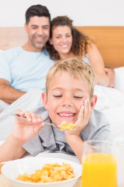 Mignonne jeune famille prenant son petit déjeuner au lit