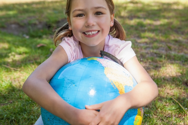 Mignonne jeune fille tenant le globe au parc