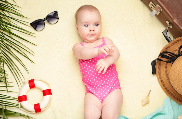 Mignonne petite fille avec des accessoires de plage sur fond clair. Vacances en mer avec bébé, concept d'été