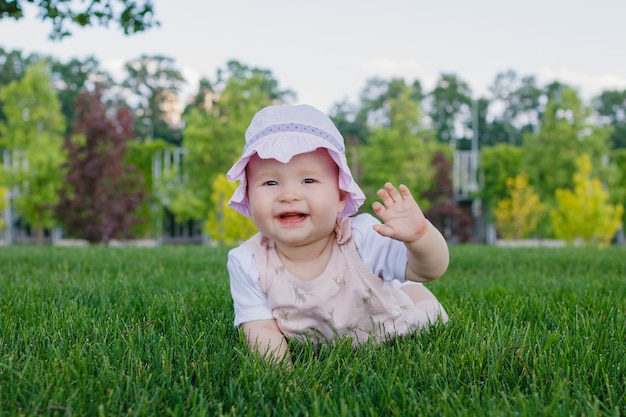 Mignonne petite fille allaitante nouveau-né allongée sur l'herbe dans un parc un jour d'été