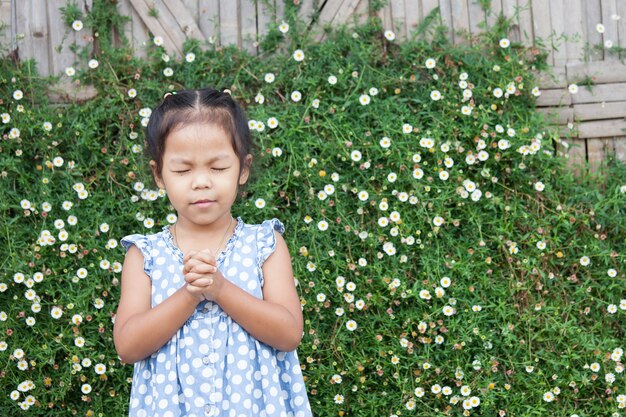 Mignonne Petite Fille Asiatique A Fermé Les Yeux Et A Plié Sa Main Dans La Prière Pour Le Concept De La Foi