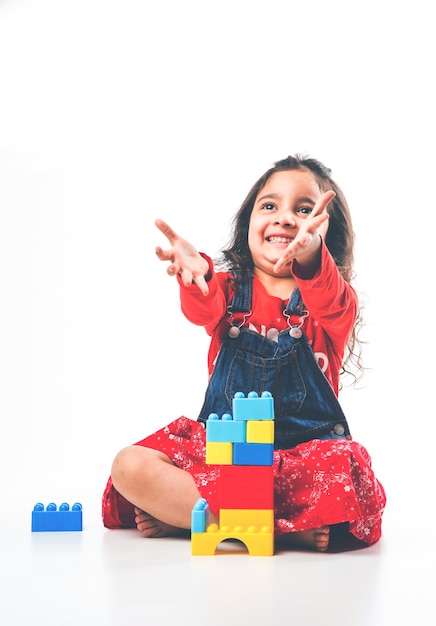 Mignonne petite fille asiatique indienne jouant avec des jouets en blocs colorés sur fond blanc