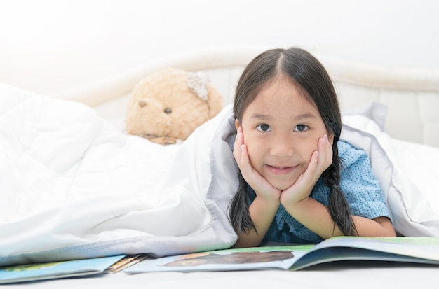 Mignonne petite fille asiatique, lecture de contes de fées sur le lit, le concept de l&#39;éducation