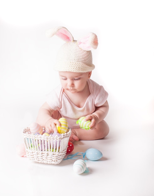 Mignonne petite fille assise dans un chapeau de lapin tricoté isolé sur blanc