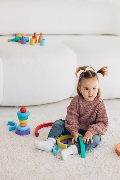 Mignonne petite fille en bas âge jouant à la maison avec des jouets en bois écologiques Heureux enfant coupant des légumes et des fruits avec un couteau jouet L'enfant jouant à des jeux éducatifs