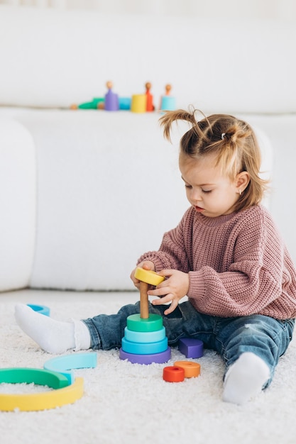 Mignonne petite fille en bas âge jouant à la maison avec des jouets en bois écologiques Heureux enfant coupant des légumes et des fruits avec un couteau jouet L'enfant jouant à des jeux éducatifs