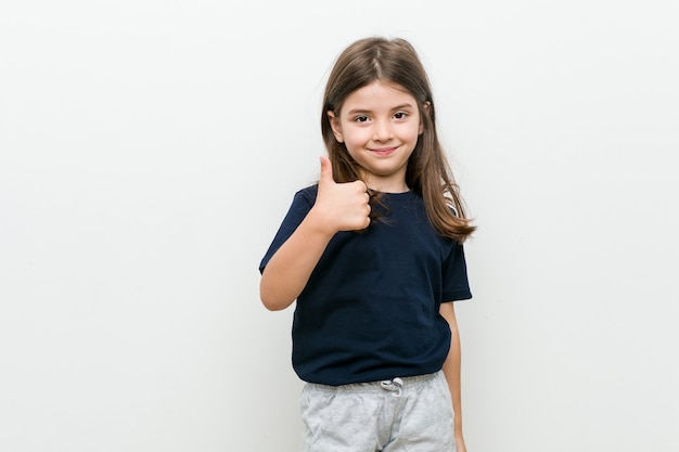 Mignonne petite fille caucasienne souriant et levant le pouce vers le haut