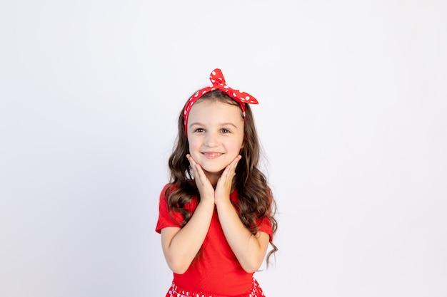 Une mignonne petite fille dans une robe rouge sur fond blanc isolé