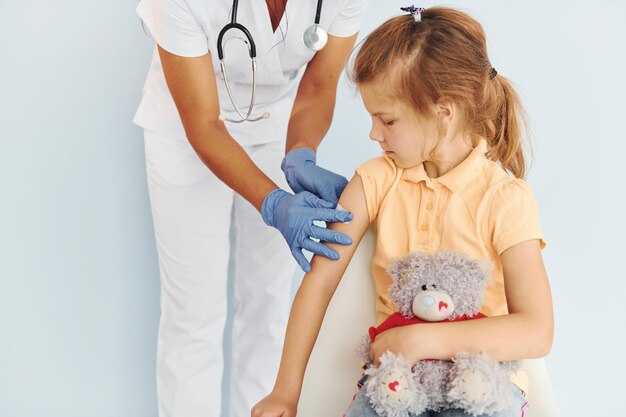 Mignonne petite fille Docteur en uniforme faisant la vaccination au patient