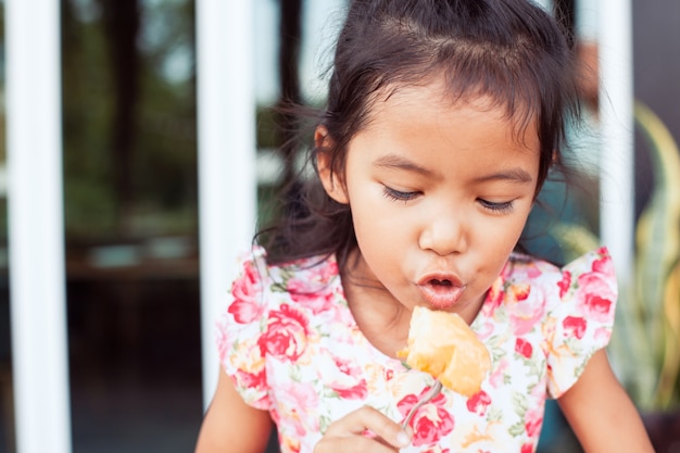 Mignonne petite fille enfant asiatique manger des toasts délicieux pour le petit déjeuner avec bonheur