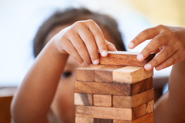Mignonne petite fille enfant asiatique prêter attention à jouer au jeu pile de blocs de bois