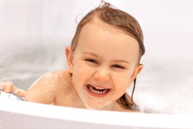 Une mignonne petite fille d'expression drôle d'enfant en riant d'avoir un bain