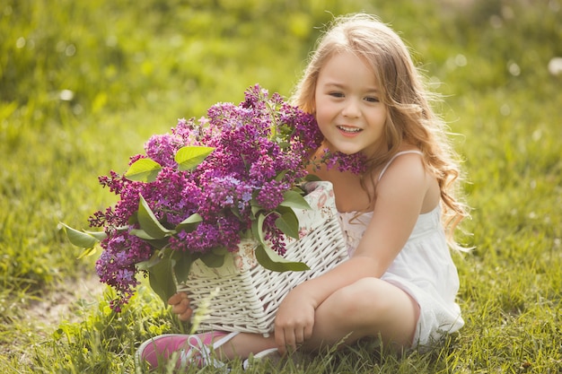 Mignonne petite fille à l'extérieur avec des fleurs de printemps. Joli enfant avec bouquet d'été lilas.