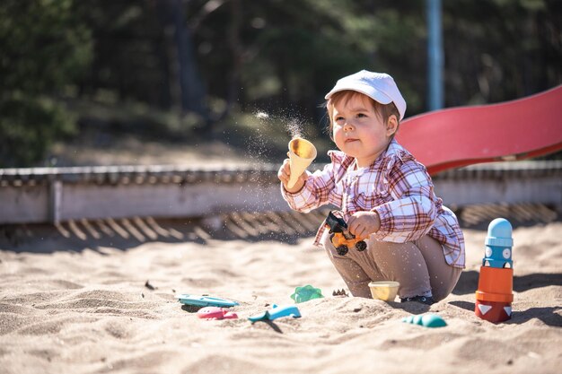 Une mignonne petite fille jouant au sable avec des jouets sur la plage un jour ensoleillé d'été